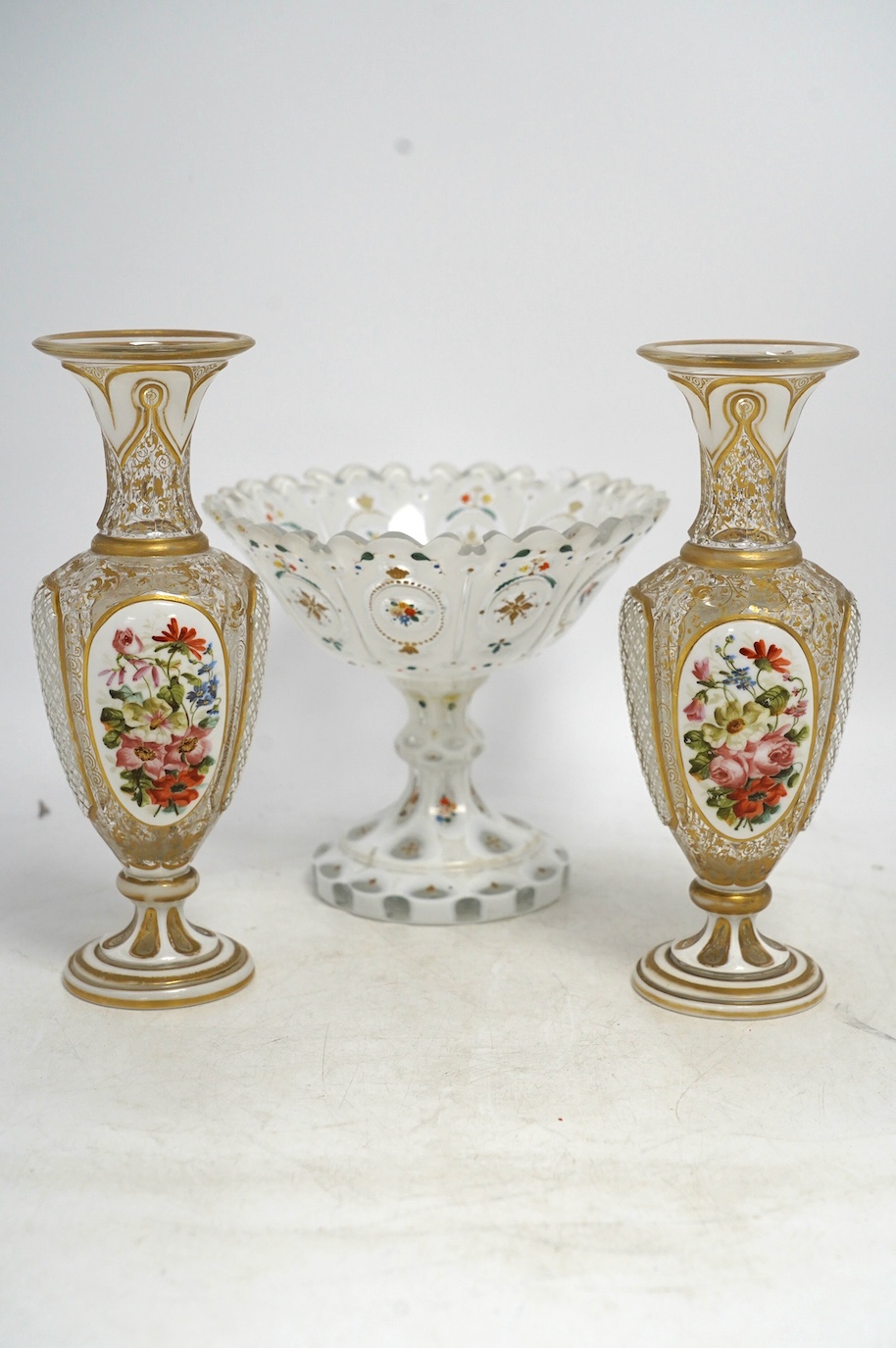 A pair of late 19th century Bohemian enamelled overlaid glass vases, and a similar overlaid glass comport. Condition - vases fair; comport poor